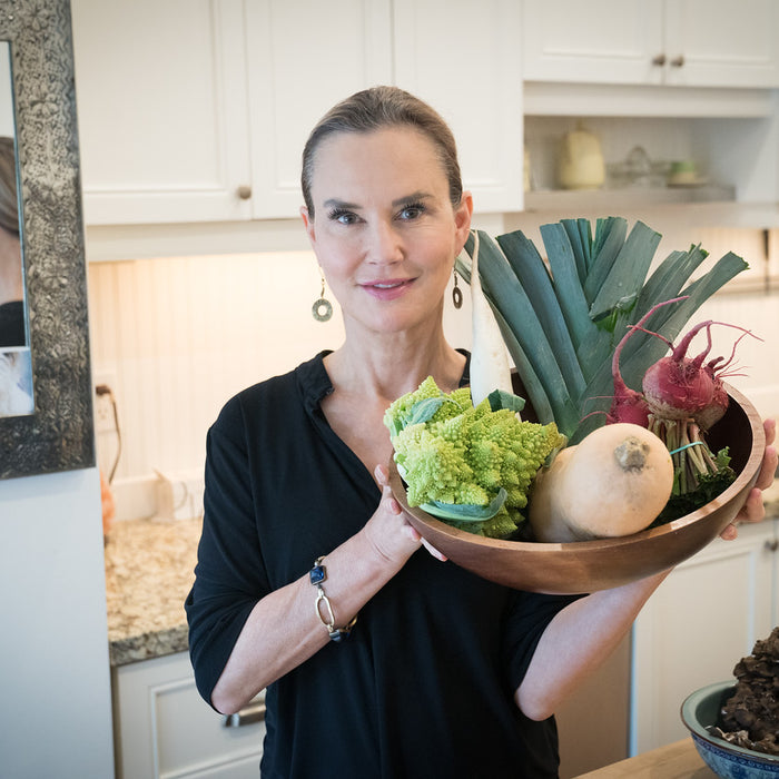 A woman with healthy skin holding a bowl of assorted vegetables
