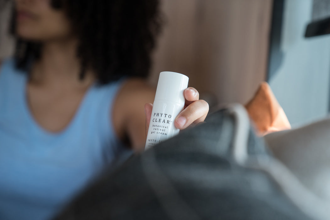 A woman holding a white bottle of natural retinol face moisturizer.