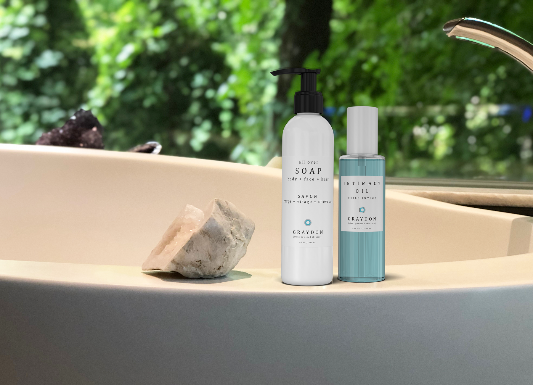 A bottle of vegan soap for sensitive skin next to a bottle of blue-coloured vegan body oil on the ledge of a chic-looking bathtub.