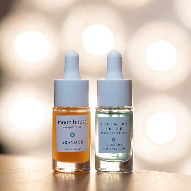 10 mL bottles of Graydon Skincare Moon Boost Serum and Fullmoon Serum with bright lights behind.