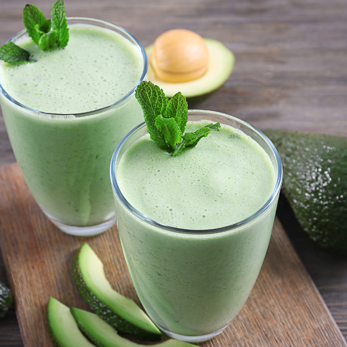 Two glasses of avocado green smoothie with mint sprig garnish