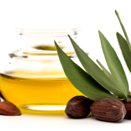 Glass Jar of Jojoba Oil with Leaves and Seeds