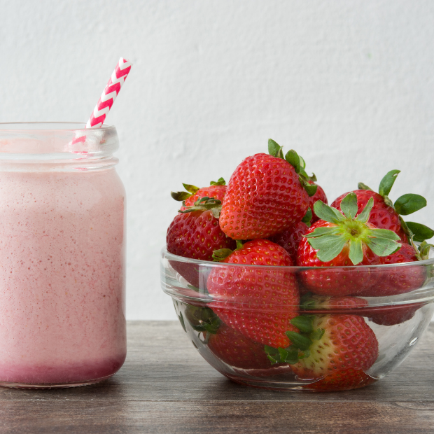Strawberry milk in a jar next to a bowl of strawberries