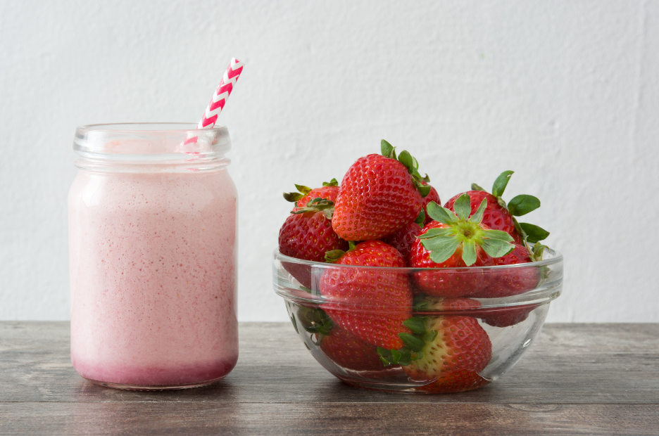 Strawberry milk in a jar next to a bowl of strawberries