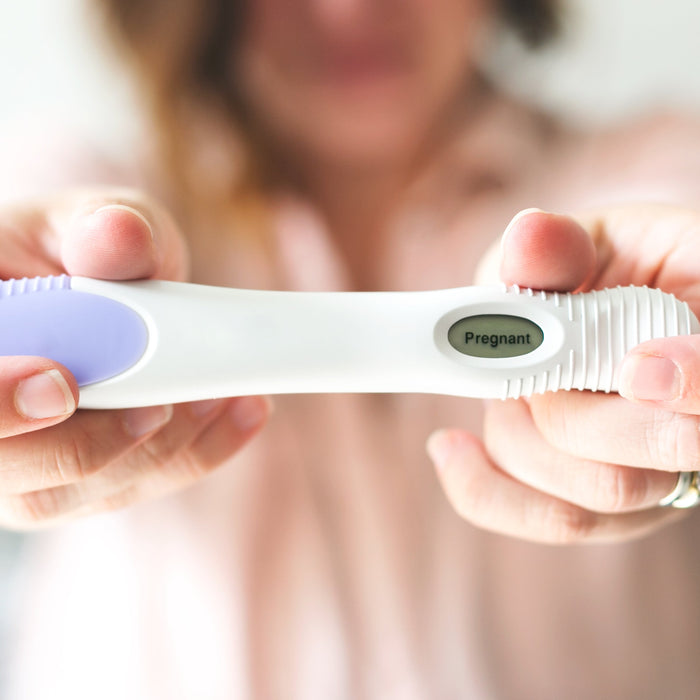 A woman holding a pregnancy test indicating "pregnant".